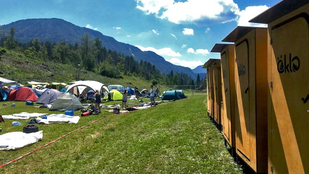 Eine Reihe öKlos steht in der rechten Bildhälfte gegen den Horizont gerichtet aufgebaut. Auf der linken Seite ist ein Zeltplatz zu sehen, auf dem einige Besucher zu sehen sind.