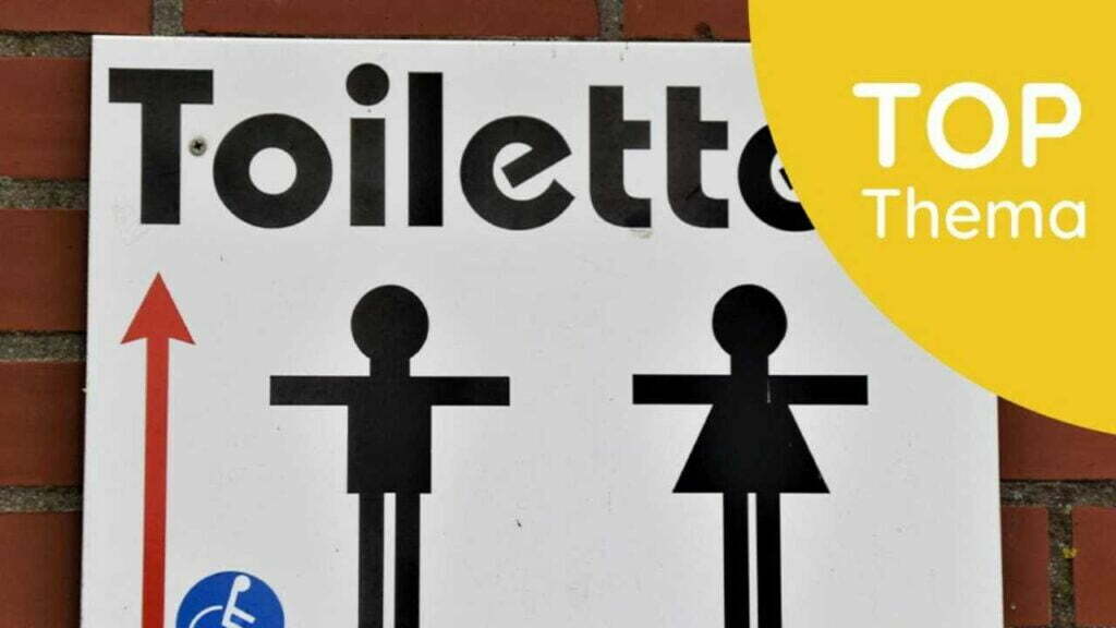 Ein Schild, das Toiletten anschreibt. Darunter sind zwei Strichfiguren zu sehen. Im oberen rechten Eck ist ein gelber Viertelkreis mit dem Text "Top-Thema" zu sehen.