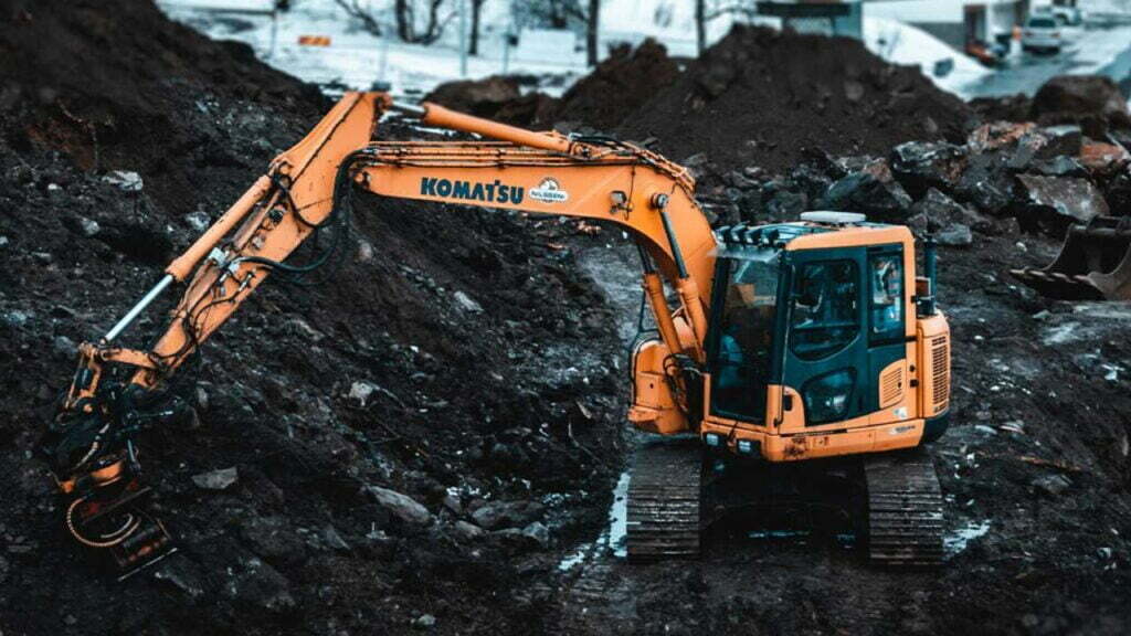 Ein Komatsu-Bagger, der gerade einen Haufen Erde umschaufelt.