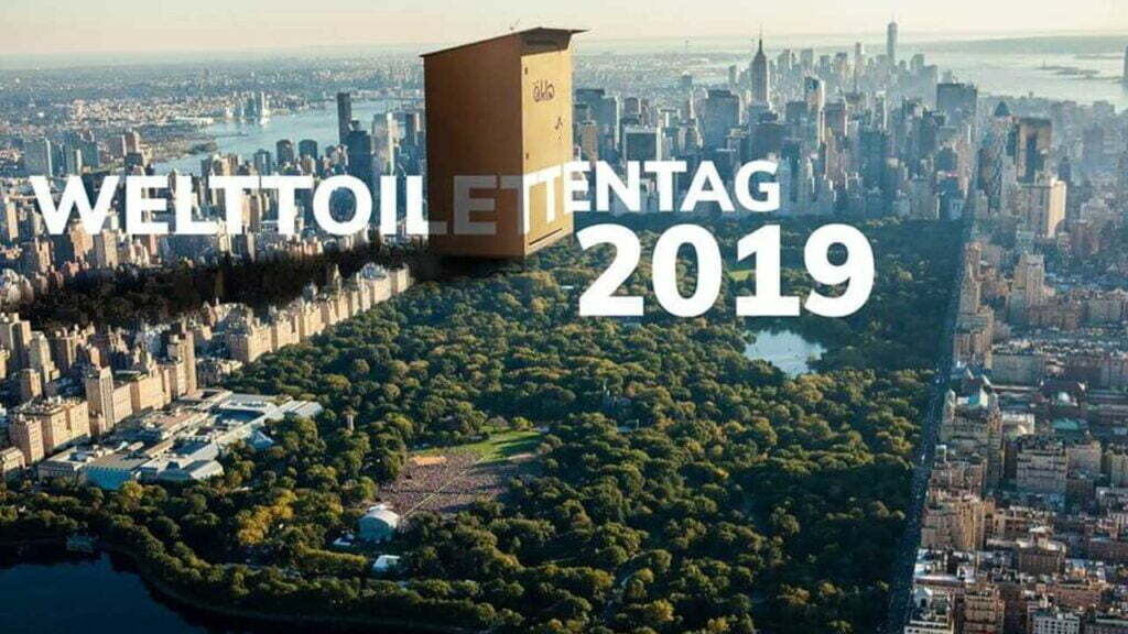 Ein öKlo, das auf einer Weitaufnahme des Central Park groß über den Bäumen steht. Der Schriftzug "Welttoilettentag 2019" ist darauf zu sehen.