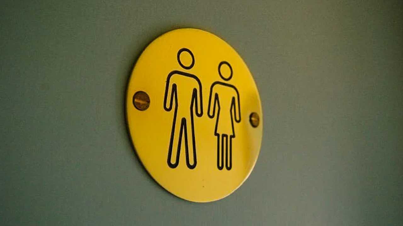 Ein Toilettenschild, auf dem zwei Personen abgebildet sind, eine mit Rock, eine ohne.