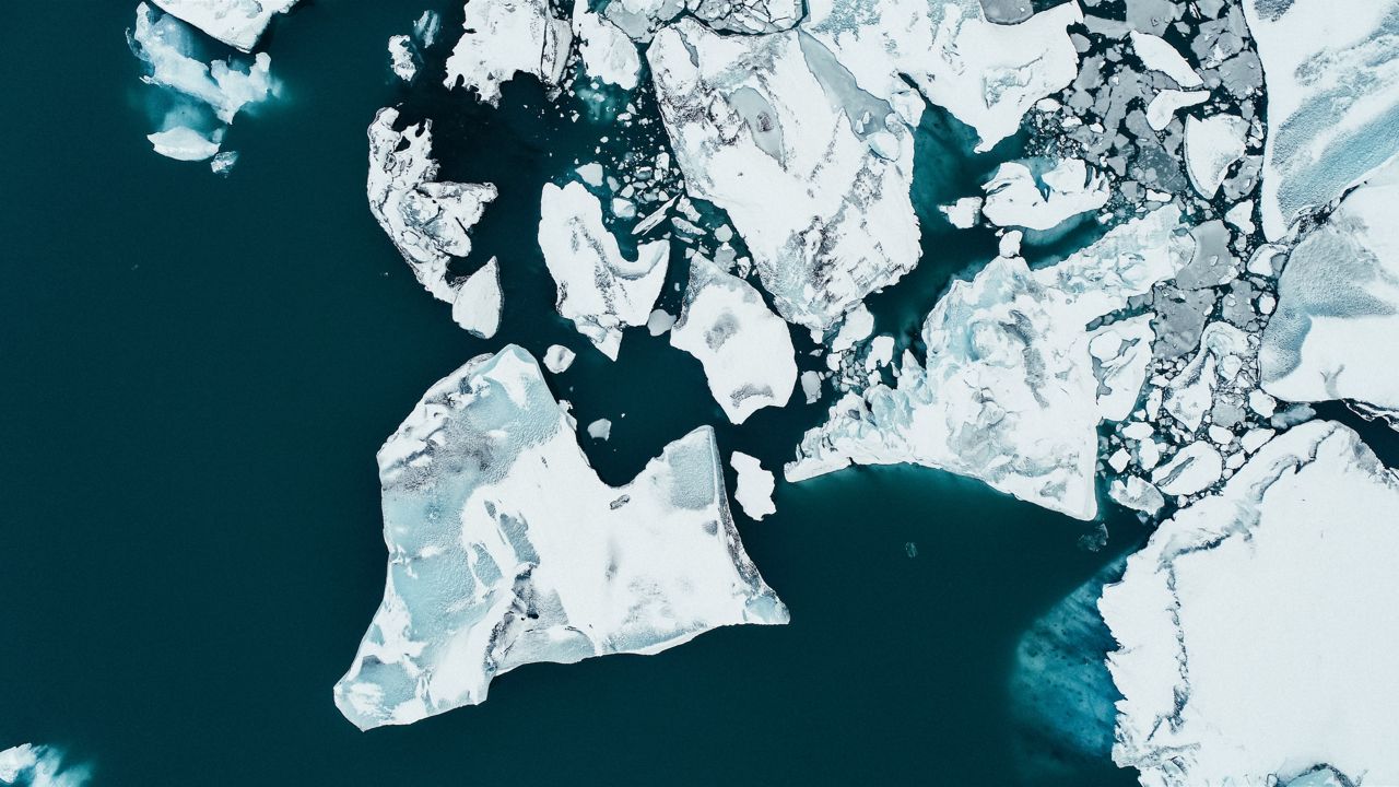Eine Eisscholle, die von einem Eisberg abgebrochen aufs offene Meer schwimmt.